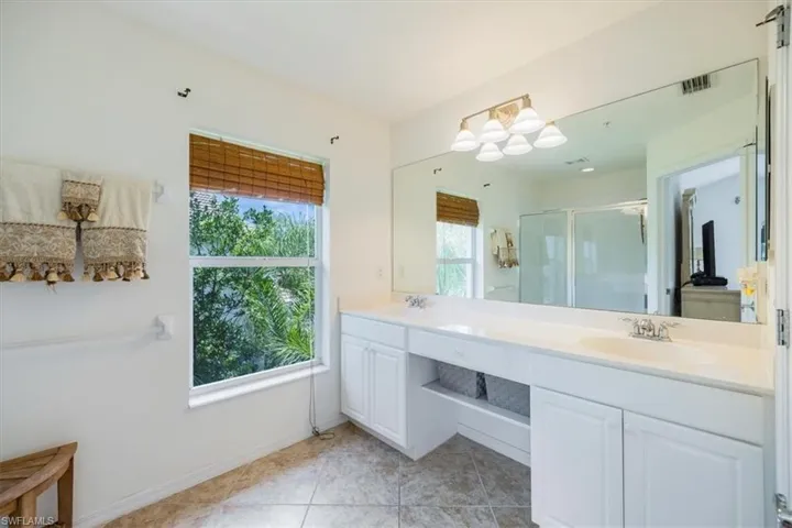 Bathroom featuring a stall shower, double vanity, and tile floors