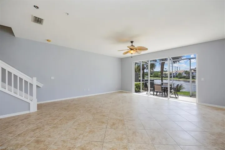 Unfurnished room with light tile patterned floors, a ceiling fan, a water view, stairway, and a pendent fire sprinkler