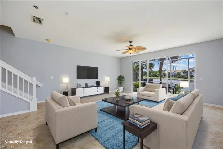 Tiled living area featuring a ceiling fan and stairs
