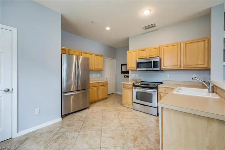 Kitchen featuring stainless steel appliances, light brown cabinetry, light countertops, tile floors, and recessed lighting