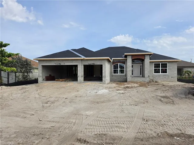 Single-story block construction home under construction, featuring a dark shingled roof, a recessed entry with an arched accent, and multiple windows with white frames