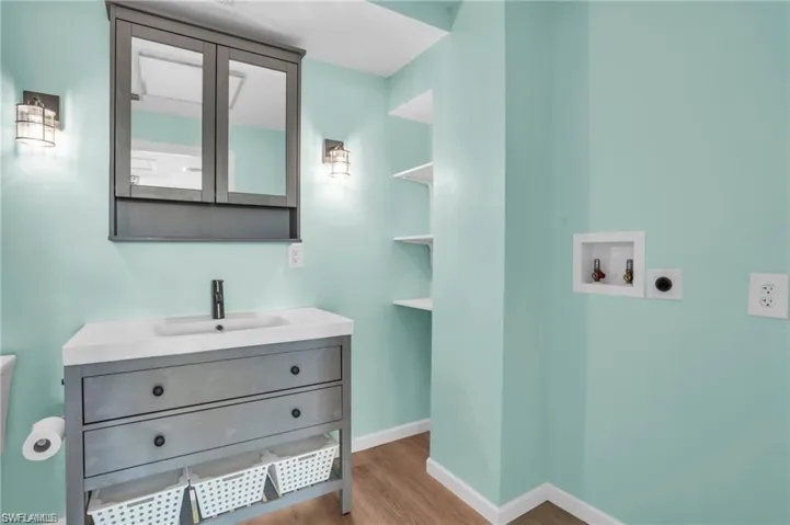Bathroom featuring baseboards, wood finished floors, toilet, and vanity
