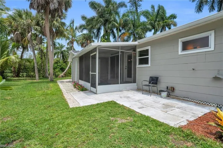 Rear view of property featuring a patio, a sunroom, and a yard