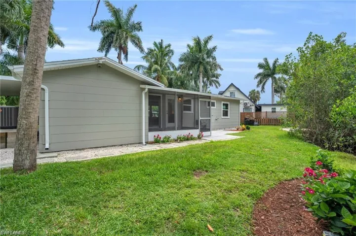 Back of property with a lawn, a sunroom, and fence