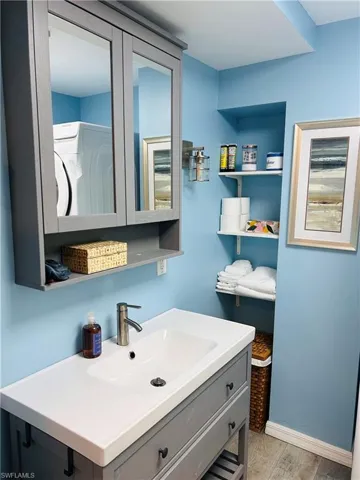 Bathroom with washer / dryer, vanity, and wood finished floors