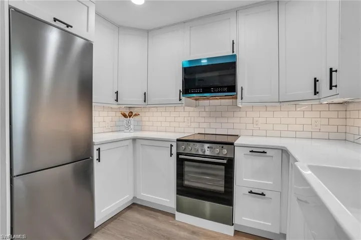 Kitchen with backsplash, light countertops, stainless steel appliances, and light wood-style flooring