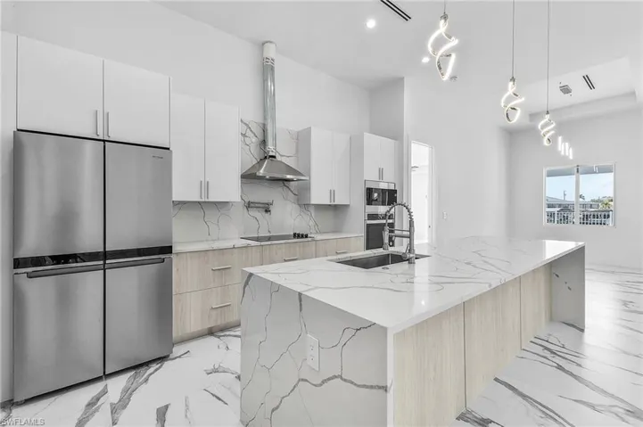 Kitchen featuring stainless steel appliances, backsplash, a sink, modern cabinets, and wall chimney exhaust hood