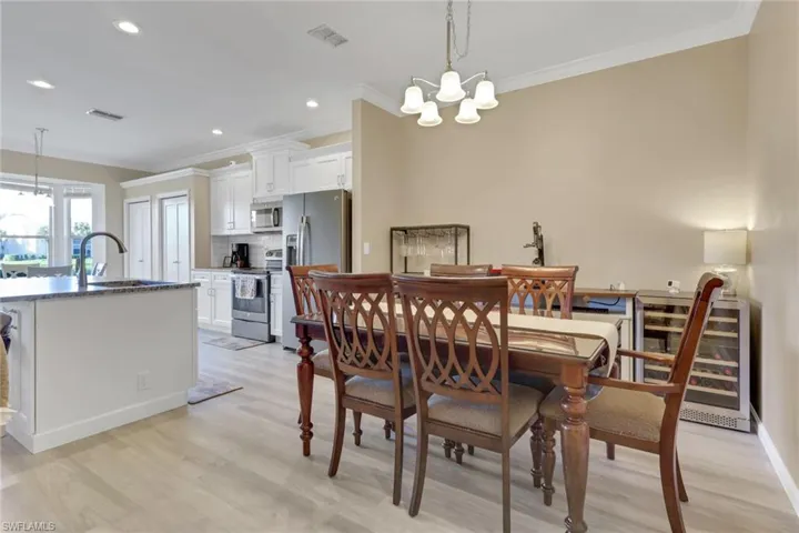 Dining area with a chandelier, ornamental molding, light wood-style floors, and recessed lighting (wine cooler does not convey)