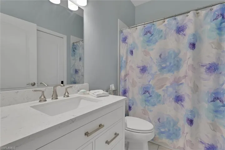 Bathroom with vanity, light tile patterned flooring, and curtained shower; granite counters and soft-close drawers and cabinetry