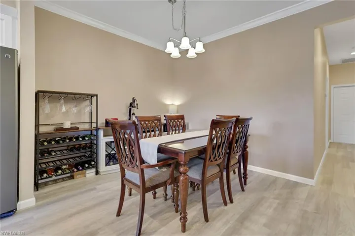 Dining room with ornamental molding, light wood-type flooring, and a chandelier