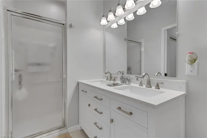 Full bathroom featuring a stall shower and double vanity; granite counters and soft-close drawers and cabinets