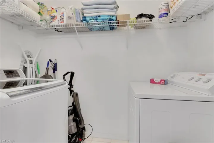 Laundry area featuring independent washer and dryer and light tile patterned floors; located off of 2nd bathroom