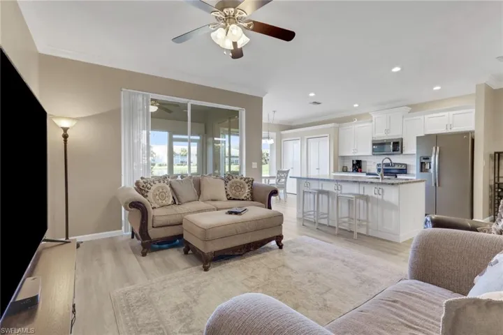 Living room with light wood-style floors, ornamental molding, recessed lighting, and a ceiling fan
