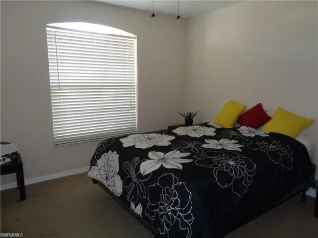 Bedroom with dark colored carpet and baseboards