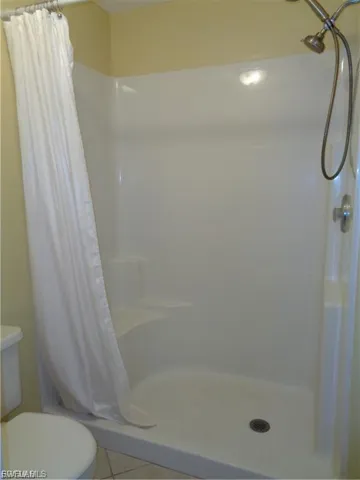 Bathroom featuring light tile patterned floors and a shower stall