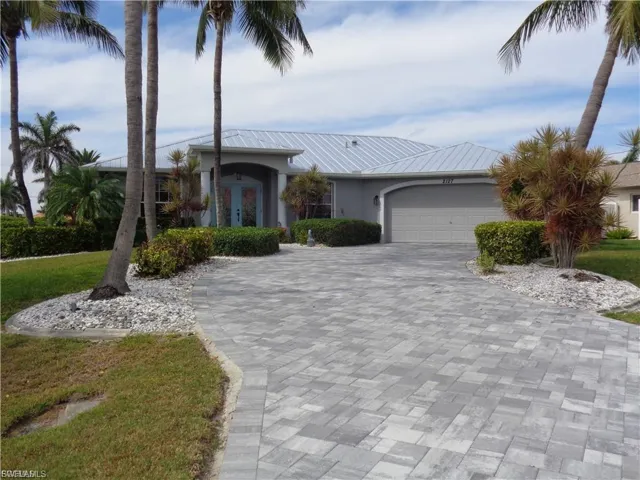 View of front of property with a garage, decorative driveway, french doors, a metal roof, and stucco siding