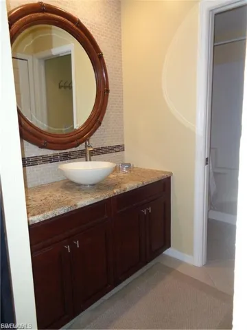 Bathroom with vanity, decorative backsplash, and light tile patterned flooring