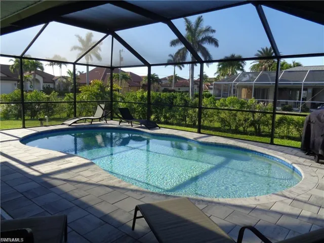 Outdoor pool with a sunroom, grilling area, a patio area, and a lanai