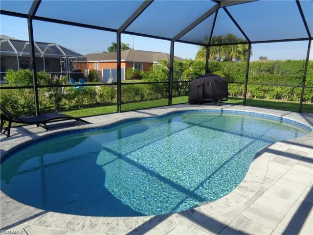Swimming pool with a sunroom, a grill, and glass enclosure