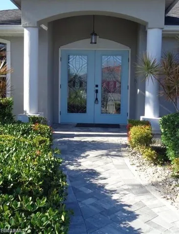 Doorway to property featuring french doors, stucco siding, and roof with shingles