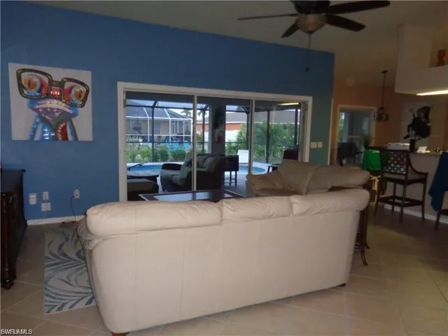 Tiled living room featuring a ceiling fan and a sunroom