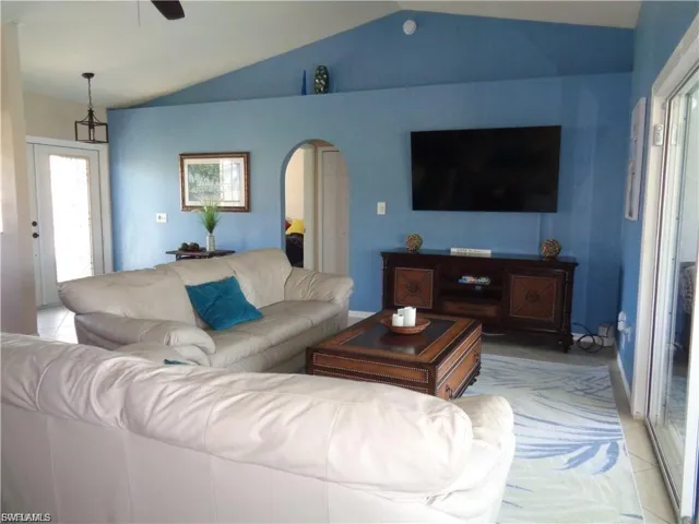 Living area with ceiling fan, arched walkways, and tile patterned flooring