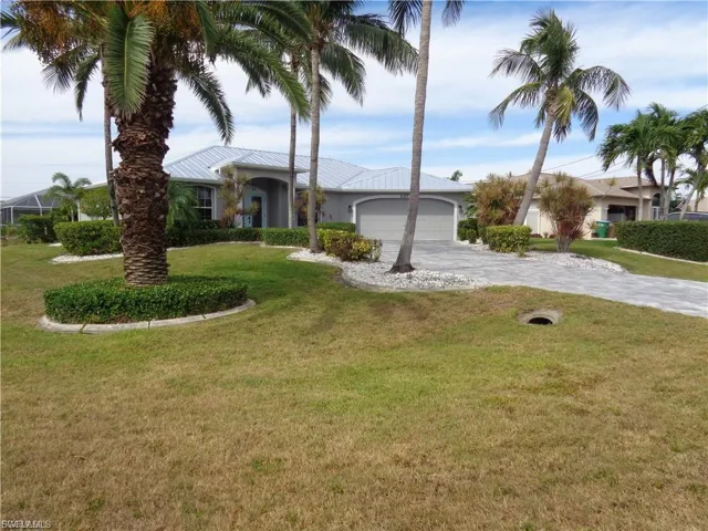 View of front facade with decorative driveway, a front yard, a garage, and stucco siding