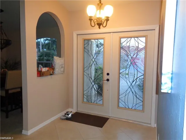 Entrance foyer with french doors, a chandelier, and tile patterned floors