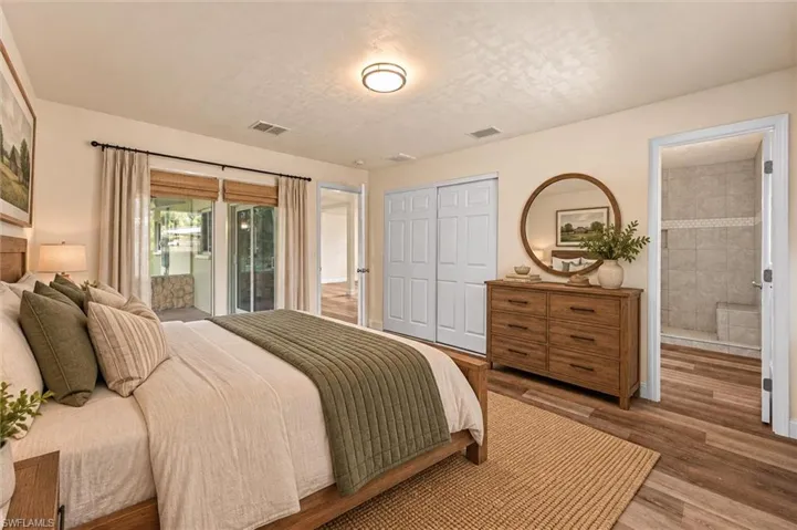 Virtually Staged Wood-finish flooring, sliding glass door with outdoor access, bifold closet doors, overhead flush-mount lighting, and an open doorway to a tiled shower with a built-in bench