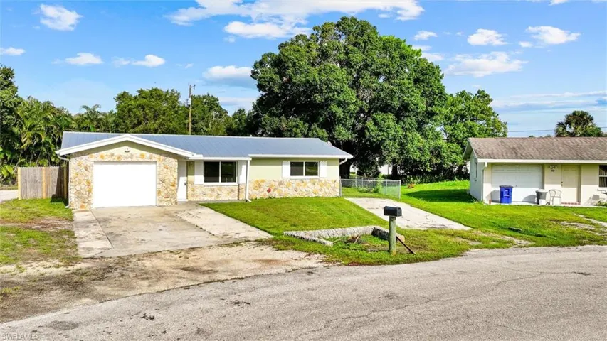 Stone facade, light green siding, metal roof, attached garage, concrete driveway