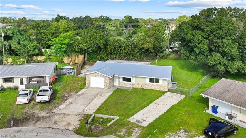 Single-story residence featuring a metal roof, stone-clad facade, attached garage, and a concrete driveway