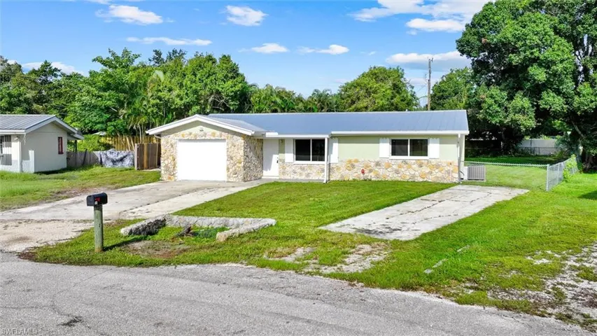 Stone veneer facade and garage, light green siding, and a metal roof