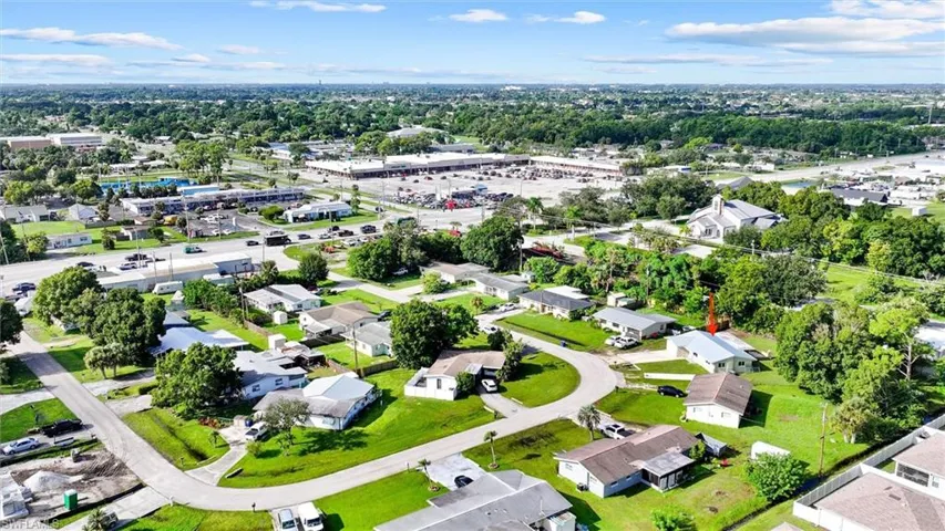 Expansive aerial perspective showcasing a residential neighborhood with surrounding commercial establishments and green spaces