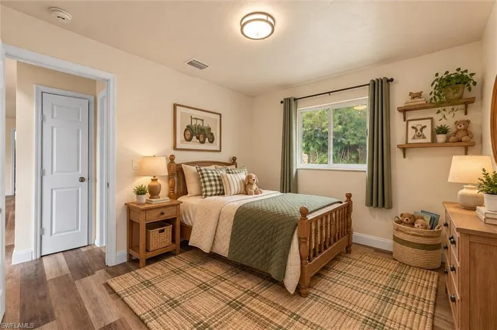 Virtually Staged Wood-finish flooring with light-toned walls, a white paneled door, and a single window