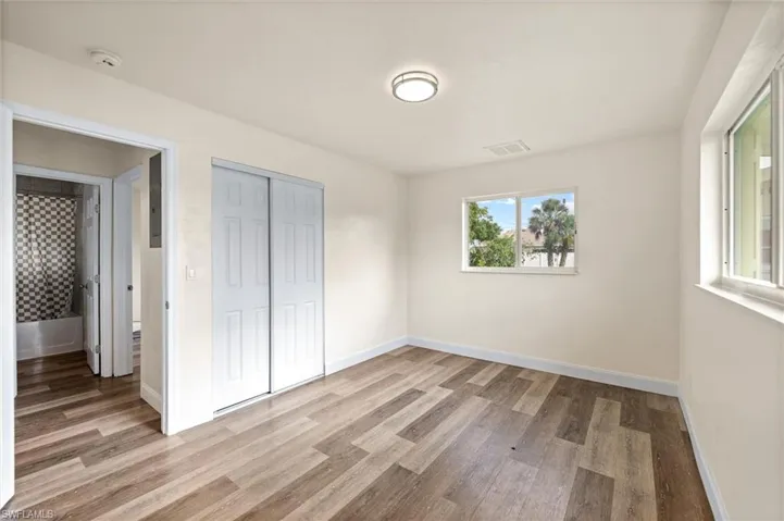 Wood-finish flooring, white walls, and a contemporary flush-mount ceiling light