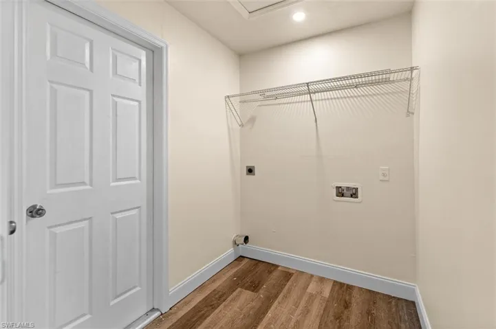 Laundry area with wood-finish flooring, white walls, and a recessed ceiling light