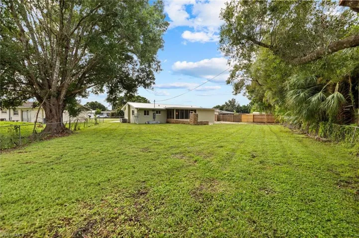 Expansive green space featuring a large mature tree and a partially fenced perimeter
