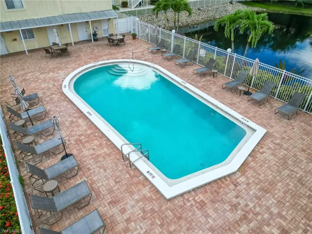 Community pool featuring a patio area, a water view, and outdoor dining space