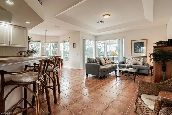 Living room featuring light tile patterned floors, a tray ceiling, and recessed lighting