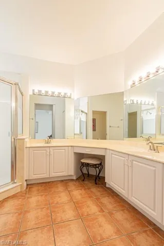 Full bathroom featuring a stall shower, vanity, and light tile patterned floors