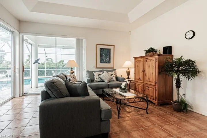Living area featuring a tray ceiling, light tile patterned flooring, and a sunroom
