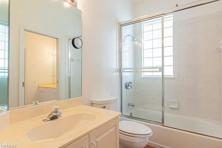 Bathroom with vanity and combined bath / shower with glass door