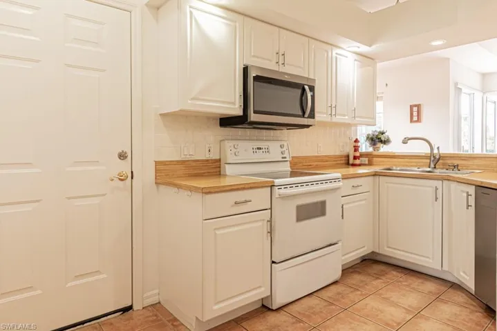 Kitchen featuring stainless steel appliances, light countertops, white cabinetry, and recessed lighting