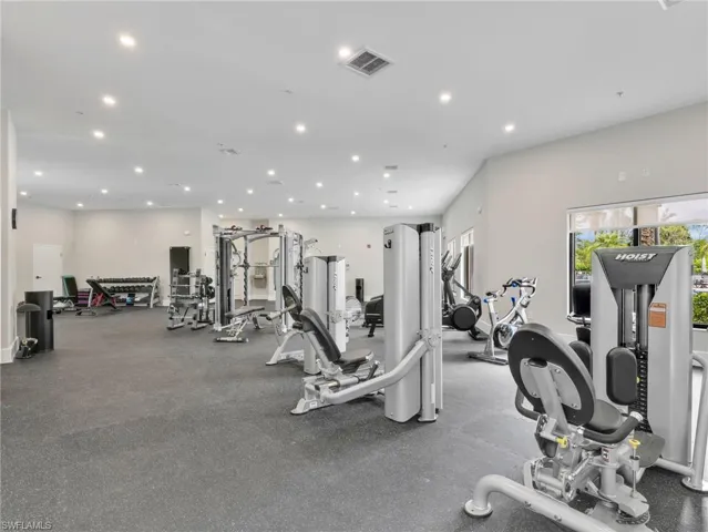 Spacious fitness area featuring recessed lighting, a durable rubberized floor, large windows, and a variety of exercise equipment