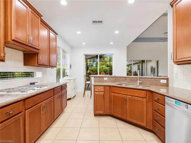 Kitchen featuring wood cabinetry, light-toned tile flooring, recessed lighting, and a built-in cooktop
