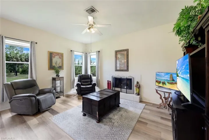 Living room with ceiling fan, light hardwood / wood-style flooring, and a fireplace