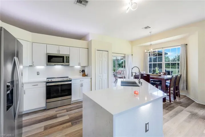 Kitchen featuring light hardwood / wood-style flooring, stainless steel appliances, sink, a kitchen island with sink, and white cabinetry