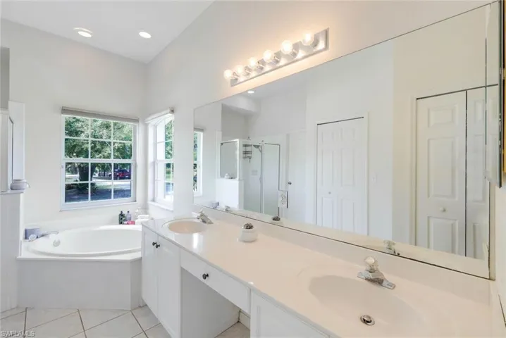 Bathroom featuring double vanity, shower with separate bathtub, and tile floors