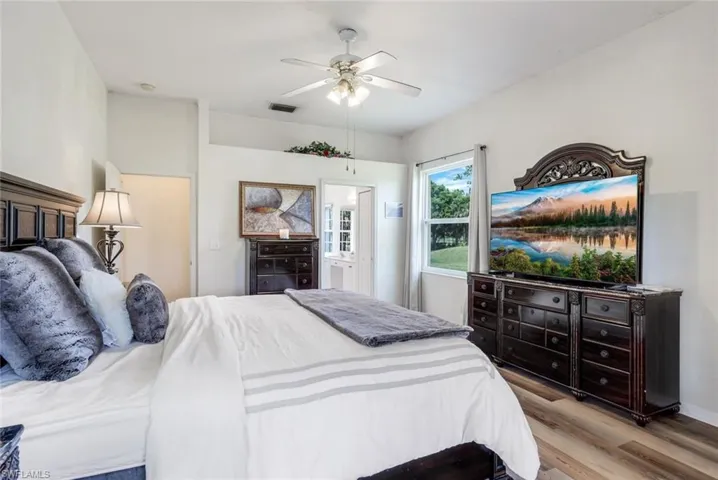 Bedroom with wood-type flooring, ensuite bathroom, and ceiling fan