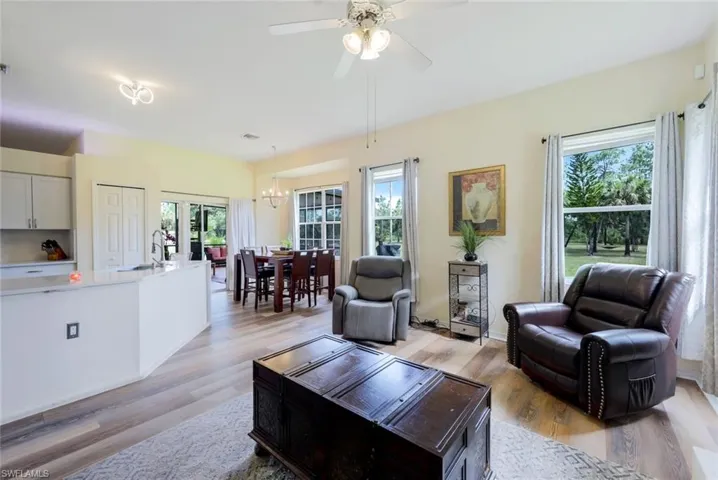 Living room with light hardwood / wood-style floors, sink, and ceiling fan with notable chandelier